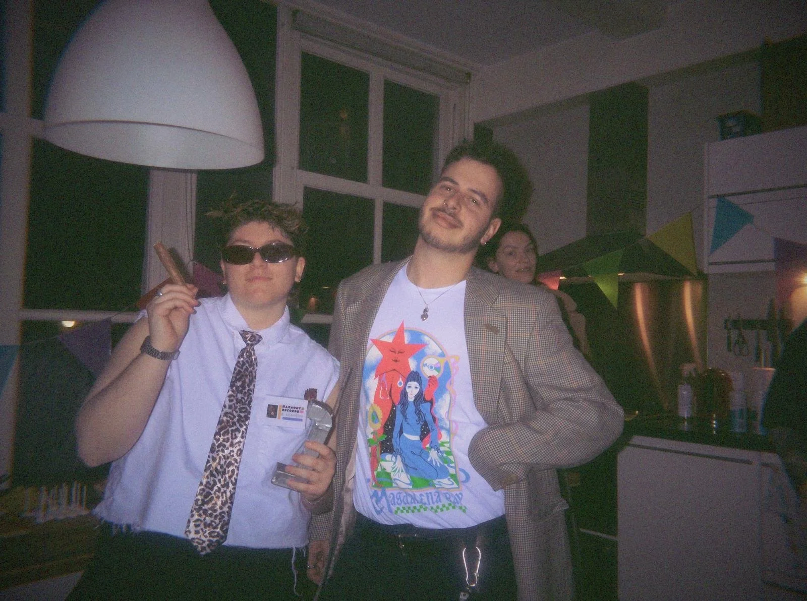 90s murder mystery party costumes with guests posing as music industry characters holding trophy and prop cigar at immersive themed party