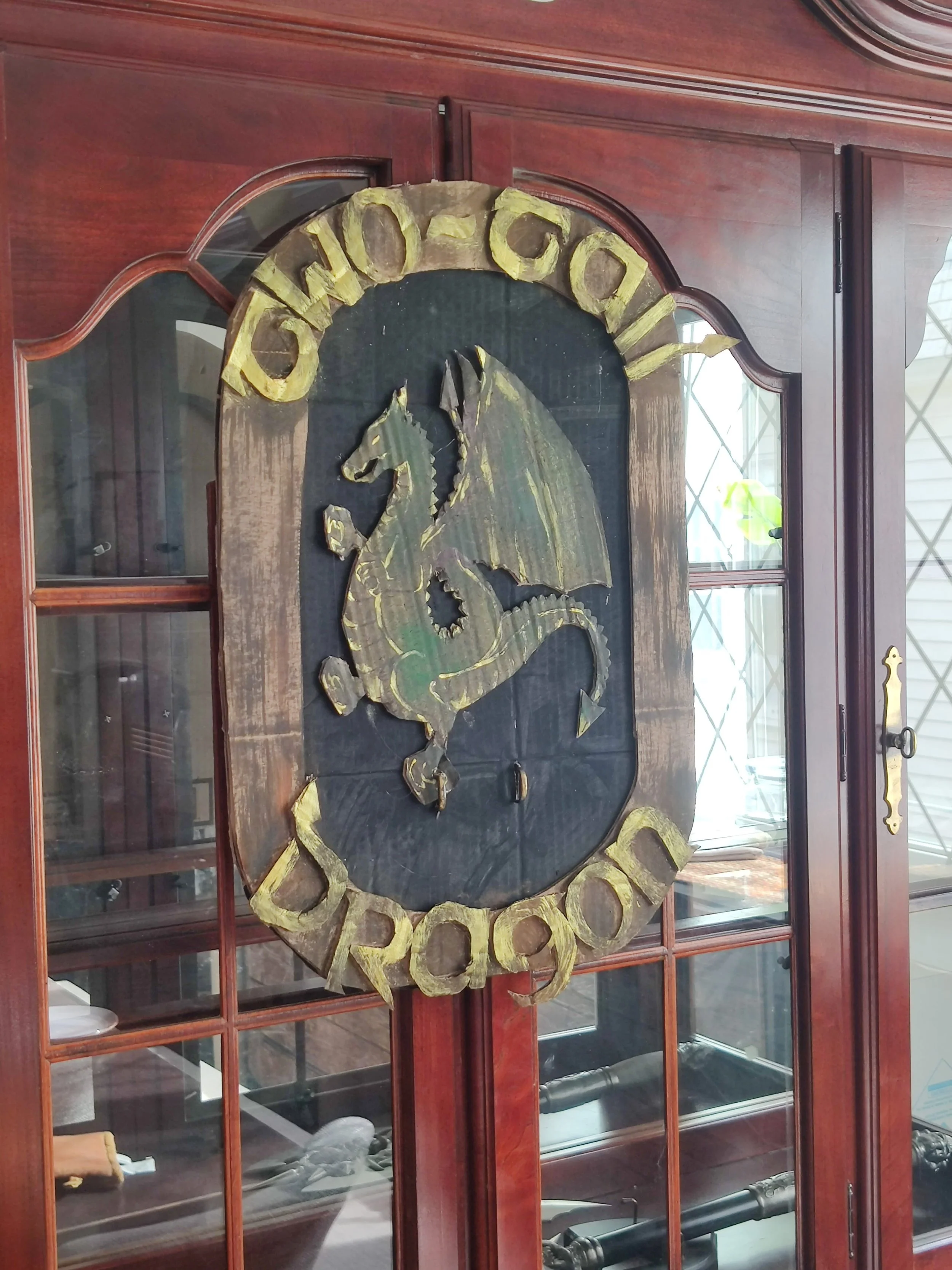 Medieval dragon crest decoration on wooden cabinet, adding immersive fantasy ambiance to a murder mystery party setting