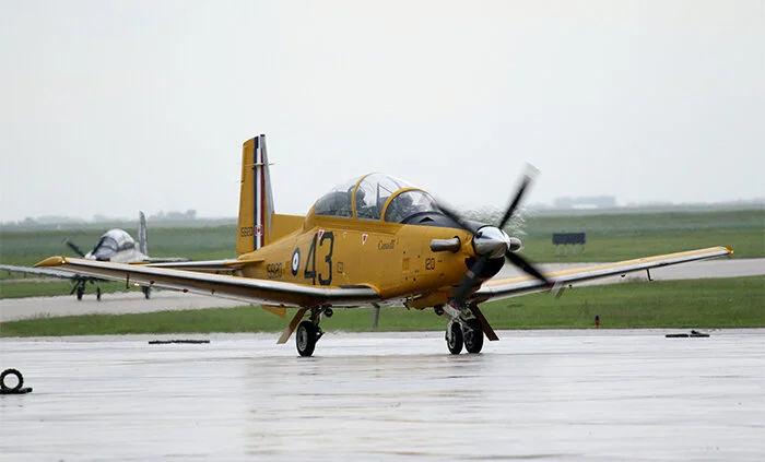 A Royal Canadian Air Force Raytheon CT-156 Harvard II freshly painted in the colours of the British Commonwealth Air Training Plan of the Second World War taxies in the rain at 15 Wing Moose Jaw, itself a former BCATP pilot training base for the Royal Air Force. The aircraft commemorates a young man who gave his life and left a gift for the world of a very special verse. Photo: Norm Swayze