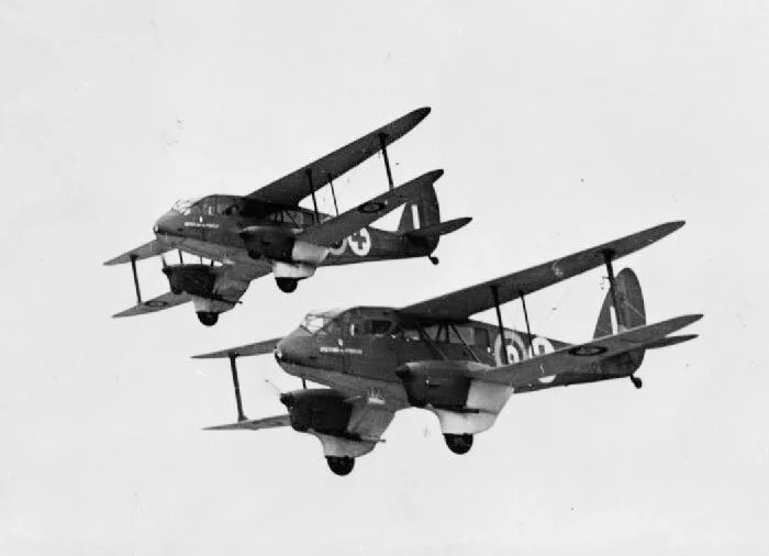 Whilst with 24 Squadron, Flight Lieutenant Trevor Southgate flew a wide assortment of transport aircraft, including the Art Deco-styled biplane transports of de Havilland—with nearly 300 hours total piloting time in the types (DH.84 Express, DH.86 Dragon, and DH.89 Dominie (Dragon Rapide)). The DH.89 Rapide and Dominie were used for both ambulance duties and VIP transport. Here we see DH.89 RAF Z7258 Women of the Empire and RAF Z7261 Women of Britain flying low over Hendon, Middlesex, the day before they were presented to No. 24 Squadron RAF by the “Silver Thimble Fund”. Originally civilian aircraft, Z7258 (formerly G-AFMH) and Z7261 (G-AFMJ) were impressed for the RAF in July 1940. Photo: Imperial War Museum