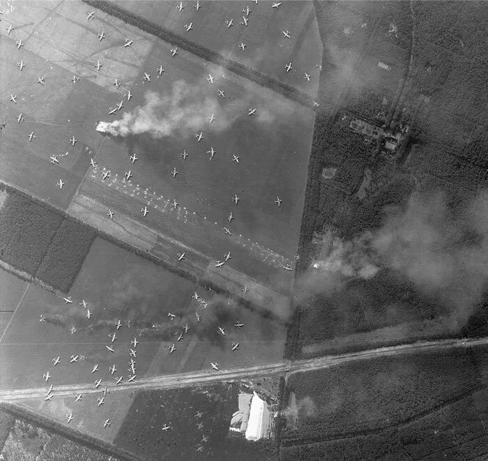 As many as 100 Horsa, Hamilcar and WACO gliders crowd farm fields near Arnhem, Holland on the opening assault. It is astonishing that they all look relatively intact and that none appear to have collided with another. A few are burning—one furiously at upper left. Photo via ArmyPhotos.net