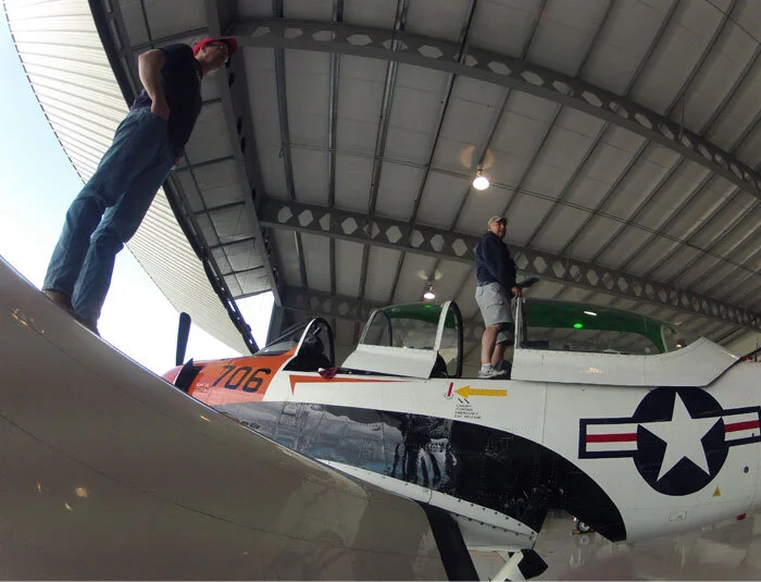 In the thoroughly modern Firefly Aviation hangar at Springbank Airport (CYBW), Todd Lemieux (Left) and Bruce Evans prepare the T-28 for the trip to Ottawa. Their casual, easy going attitude belies a professionalism born of many years of flying. Photo: Dave O'Malley