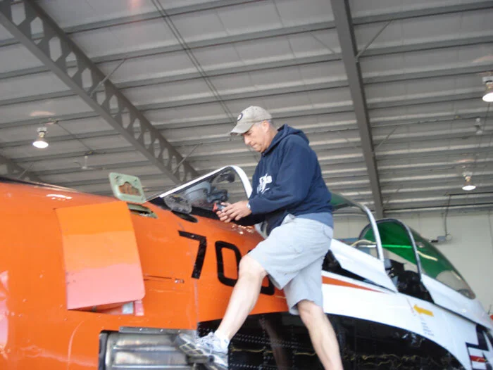 Bruce Evens checks the oil in the big 1,425 hp Wright R-1820-9 radial engine. A foot peg can be extracted from the exhaust shield to allow maintainers to step up to the oil filling access panel. Photo: Dave O'Malley