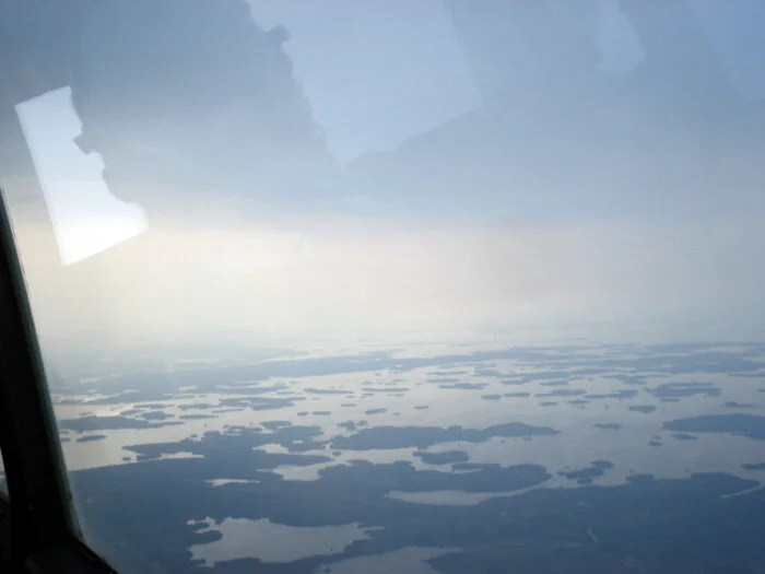 Early on the morning of the second day, we leave Winnipeg on a choppy morning in a murk made of glowering cloud and forest fire smoke. We can smell the fire in the cockpit. Here, we overfly the endless lakes, bays and channels of the rugged Kenora and Lake of the Woods Region which straddles the Manitoba-Ontario border. Looking down on the watery landscape, I think about the emergency vests, out of reach in the baggage compartment. Bruce assures me that the T-28 can make any land visible in the triangle described by the line from the nose to the wingtip to the fuselage. Of course, all that land is covered by heavy forests and ancient rock formations, but he also assures me that the rugged airplane could take on any of Canada's boreal forests. Photo: Dave O'Malley