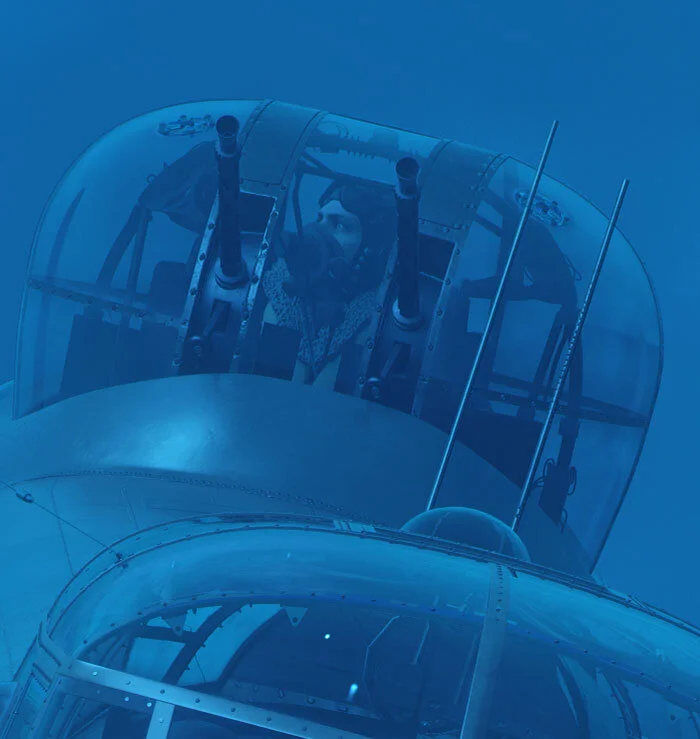 Above the fuselage, exposed to the wild and threatening blue night around him, a depiction of Warrant Officer Robbie Aitken scans the darkness for signs of the enemy or the dangerous proximity of other 15 Squadron aircraft. Pupils dilated in the glo…