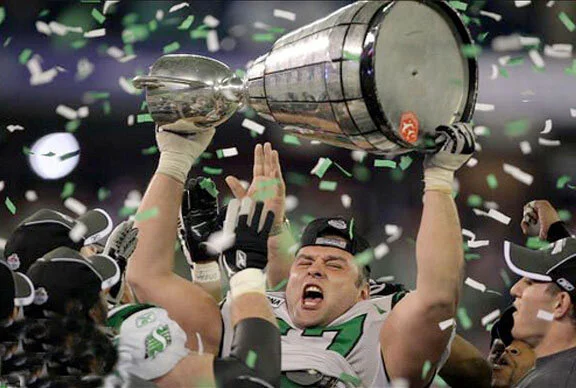 Saskatchewan lineman Mike Abu-Mechrek hoists the cup high with the zapper in plain view—the Snowbirds were cheering equally loud in their Skybox. Photo by Harry How via Rider Nation at flickr.com