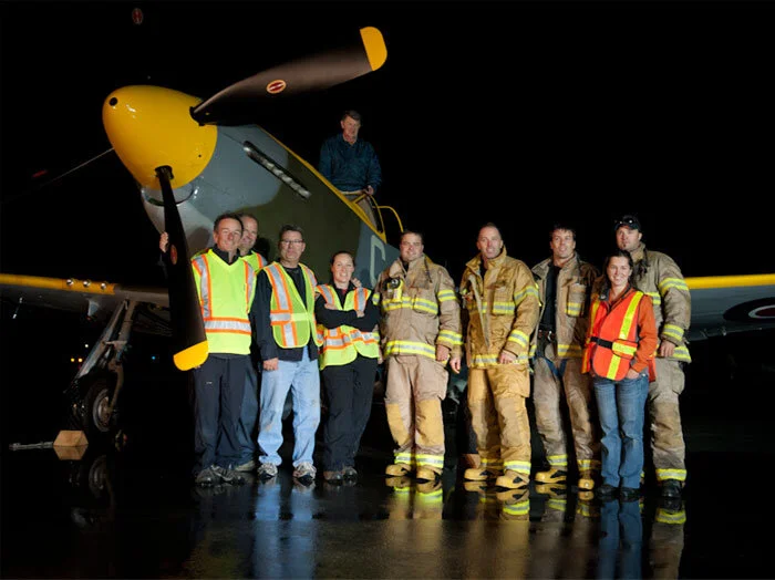 The organizers of the photo shoot, Richard Allnutt and Peter Handley, owe much to the cooperation of the City of Gatineau and its fire department, and the VWC maintenance crews and pilots for making the shoot the success that it was. Here we see pilot John Aitken and his Mustang posing with VWC maintainers (left) and Gatineau fire fighters... and the one, the only Heather Fleck (in orange). Photo Peter Handley