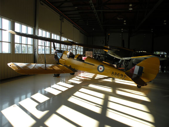 Heralding the start of another day of sharing the collection; the Tiger Moth sits next to the hangar doors, capturing the early morning light across her yellow wings.&nbsp; Photo: John Davies.
