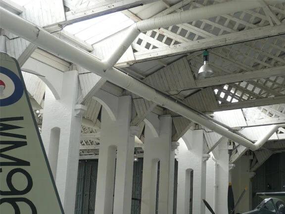 Much of what is special about Duxford lies in the intact wooden Belfast truss hangars of First World War vintage. These are listed buildings (meaning that in the UK they have preservation status - wish we could do this for the same vintage hangars at Borden). Vintage warbird operations like Howard's Historic Aircraft Collection, The Fighter Collection and others conduct restoration and maintenance on an eclectic collection of aircraft under the same composite trusses and masonry columns as did the men of the RFC in the First World War and the RAF during the Battle of Britain.  Photo: Dave O'Malley