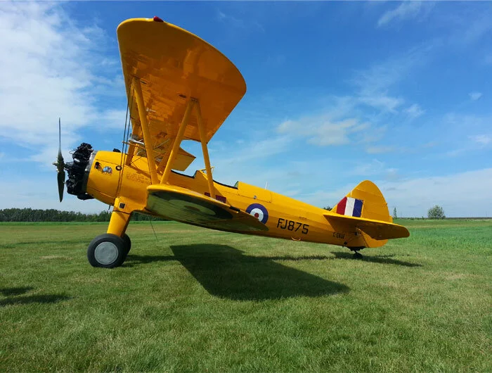 The Warrant Officer Harry Hannah Boeing PT-27 Stearman (Kaydet)—the Inspiration Machine. Of all the elementary flying training aircraft on the British Commonwealth Air Training Plan (BCATP), Kaydet, though a larger, more powerful biplane than the more delicate Tiger Moths and Fleet Finches also in use at the time, was in service for only a few months. The Kaydets were delivered for use in Royal Air Force (RAF)-run schools in Alberta only, but without many of the options requested by the RAF for instruction in the extreme cold of the Canadian climate—the most important shortcoming being the lack of an enclosed cockpit. Pilots were issued leather face masks to prevent frostbite in the slipstream of the open Stearman cockpit. Despite these problems, they were employed until much better equipped Fairchild Cornell trainers could be supplied. After 18 months, they were returned to the United Sates, where they served as USAAF trainers. RAF student pilots, who trained on the Stearman, look back fondly on the memory of this superb handling trainer and consider themselves amongst an elite group in the BCATP. The Vintage Wings Stearman, a rare BCATP veteran, wears the markings it once wore (FJ875) when in the service of the BCATP at No. 32 EFTS, Bowden, Alberta. Photo: Todd Lemieux, Yellow Wings Stearman Team