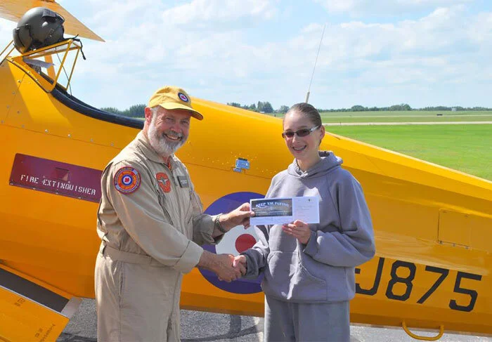 Yellow Wings pilot Derek Blatchford, himself a long time cadet instructor and tow pilot, shakes hands with his next passenger, 14-year-old Amanda Loeffen, a Flight Corporal at 38 “Anavets” Squadron in Prince Albert, Saskatchewan. “I thank Vintage Wings and their generous sponsors and donors for reassuring me that flying is what I want to do with my life, I will remember that moment forever,” said Loeffen after her first flight in an open-cockpit aircraft. Photo: Yellow Wings Stearman Team