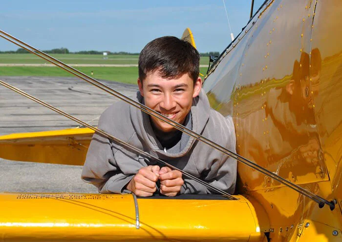 Flight Sergeant Darcy Wong of Saskatoon, Saskatchewan, a 16-year-old from 107 “Spitfire” Royal Canadian Air Cadet Squadron has some mighty grand plans for his future, and if he accomplishes even half of them, the world will indeed be a better place. “My experience from Vintage Wings is definitely one of the best things I’ve done in cadets, if not the best. When I was up in the air, it felt like a second home. The best part was everything from the takeoff to the landing, it was simply majestic. In five years, I plan to be finishing my mechanical engineering degree and going to achieve a degree in Business and Administration as well as going into commerce. After cadets, I plan to pursue my interest in business. After I have completely finished with school, I plan to invent a car that does not pollute and sell it worldwide, then moving onto other projects in infrastructure and other means of transportation. After that, I plan to completely revolutionize the energy industry into a 100% renewable grid and change the world. I would like to thank those who made this experience possible for me and to say please keep helping this program because the change starts small and it will only get bigger. This program is small in terms of a world scale but I have every belief that it will only get bigger.” 40 years from now, we would like to think that the world was saved by Darcy because of the inspirational spark we gave him. Photo: Yellow Wings Stearman Team