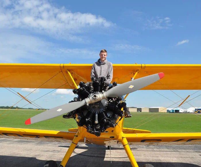Young Kim Gosbjorn from Bon Accord, Alberta, a 15-year-old cadet from 524 “Sturgeon” RCACS poses straddling the cowlings of the Stearman in which he just went for a ride at Penhold summer camp. Kim tells us, “I am on a six-week Air Rifle Marksmanship Instructor course at Penhold Air Cadet Summer Training Centre and I am having an amazing time. I get to have lots of time on the range and all of the flight staff and other cadets are really awesome. Flying with Vintage Wings was easily the coolest thing I’ve ever done through Cadets. I know that it is a once-in-a-lifetime opportunity and I will remember it for the rest of my life. The best part was definitely when I was able to control the plane for a little bit. I hope to get my own pilot’s licence through cadets and in five years, I hope to be in university preparing to join the RCAF and becoming a pilot in the military. To all the sponsors and generous donors, you have given a lot of cadets a once-in-a-lifetime opportunity and you have helped make dreams come true for a lot of cadets.” Photo: Yellow Wings Stearman Team