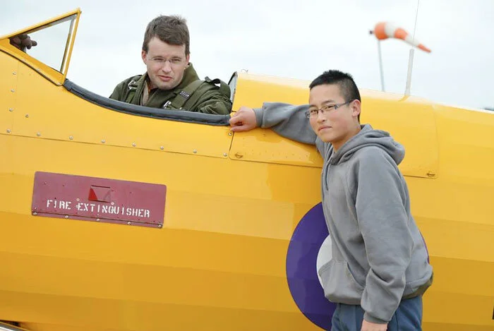 Sergeant Jessen Liang, 16 years old, from Calgary, Alberta, is from 604 “Moose” Squadron and was flown in the Stearman by Vintage Wings pilot Jeff Bell. Of his surprise flight in the Stearman, he had this to say, “Not knowing what to expect, we marched over to the airport to receive a small pre-flight briefing. Shortly thereafter, I was led by my pilot out onto the apron, where a Boeing Stearman Trainer was waiting for us. I was belted in, and after a bit, the radial engine was cranking and getting us into the air. We flew a circuit, air blasting through the open cockpit. The best feeling was that of the raw exhilaration from having a once-in-a-lifetime chance to have a flight in a piece of Canadian history. The experiences I have gained here are unforgettable, and will definitely help me in my career and education, both in Cadets and out. In 5 years, I will be in my third year of University, where I want to be studying Aviation Technology and Mechanical Engineering or other Technological-related courses. Cadets and especially the matchless opportunities that I have gotten from the program such as this one, will irrefutably help me in my future career. Thank you to Vintage Wings and their sponsors, Raytheon, for a great experience, a great program, and a great flight! The experience has definitely inspired a track for me to continue on into an Aviation-related career.” Photo: Yellow Wings Stearman Team