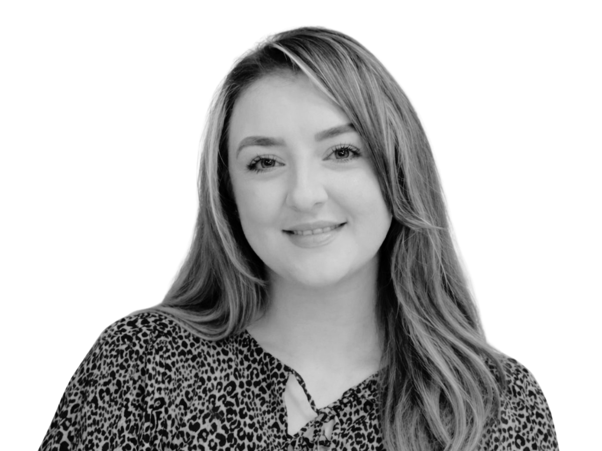 Black-and-white headshot of Holly, a team member with long straight dark hair, and smiling at the camera.