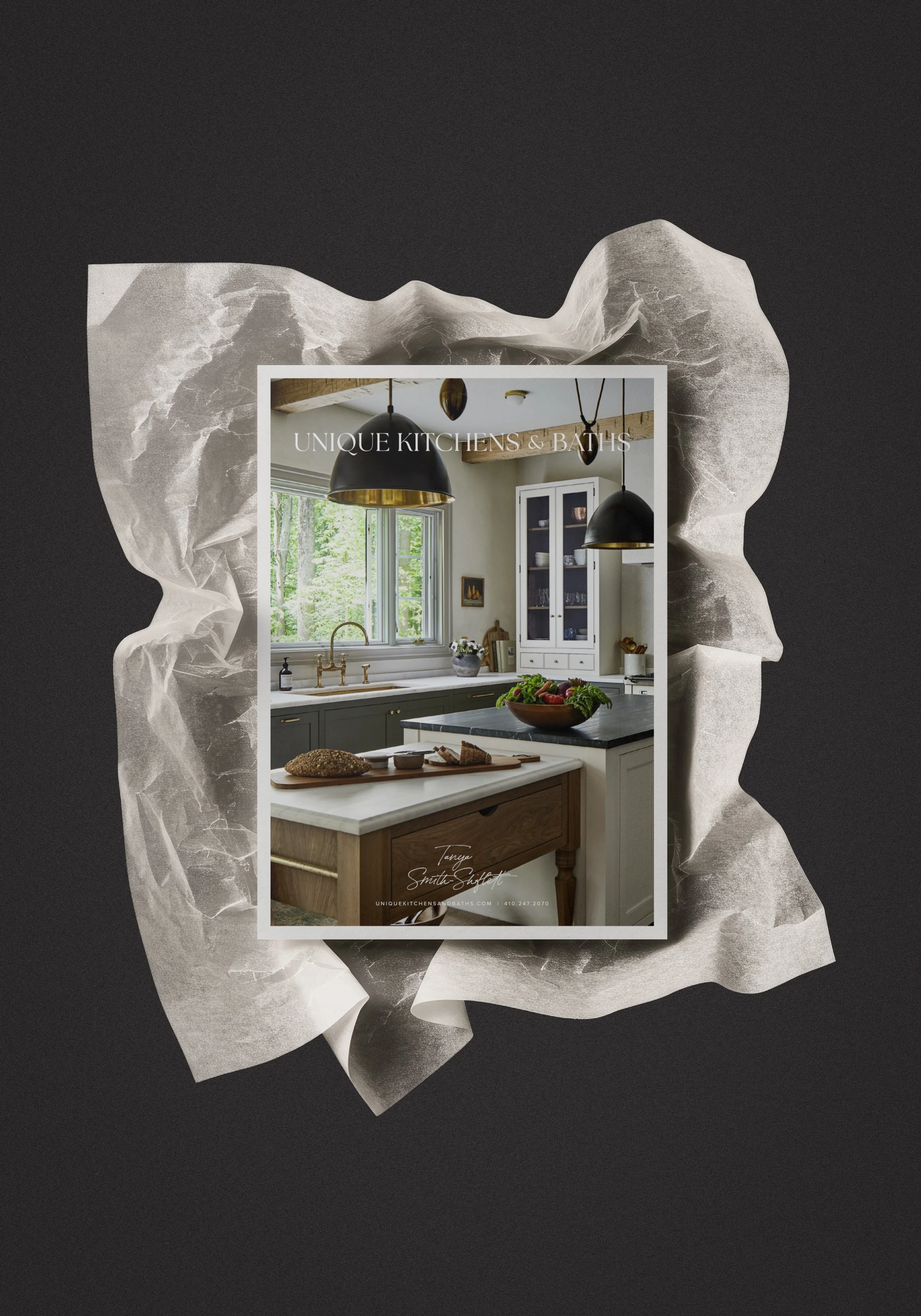 A magazine cover featuring a kitchen with natural light, black pendant lights, white cabinets, a window with green trees outside, and a kitchen island with a bowl of salad and some bread.