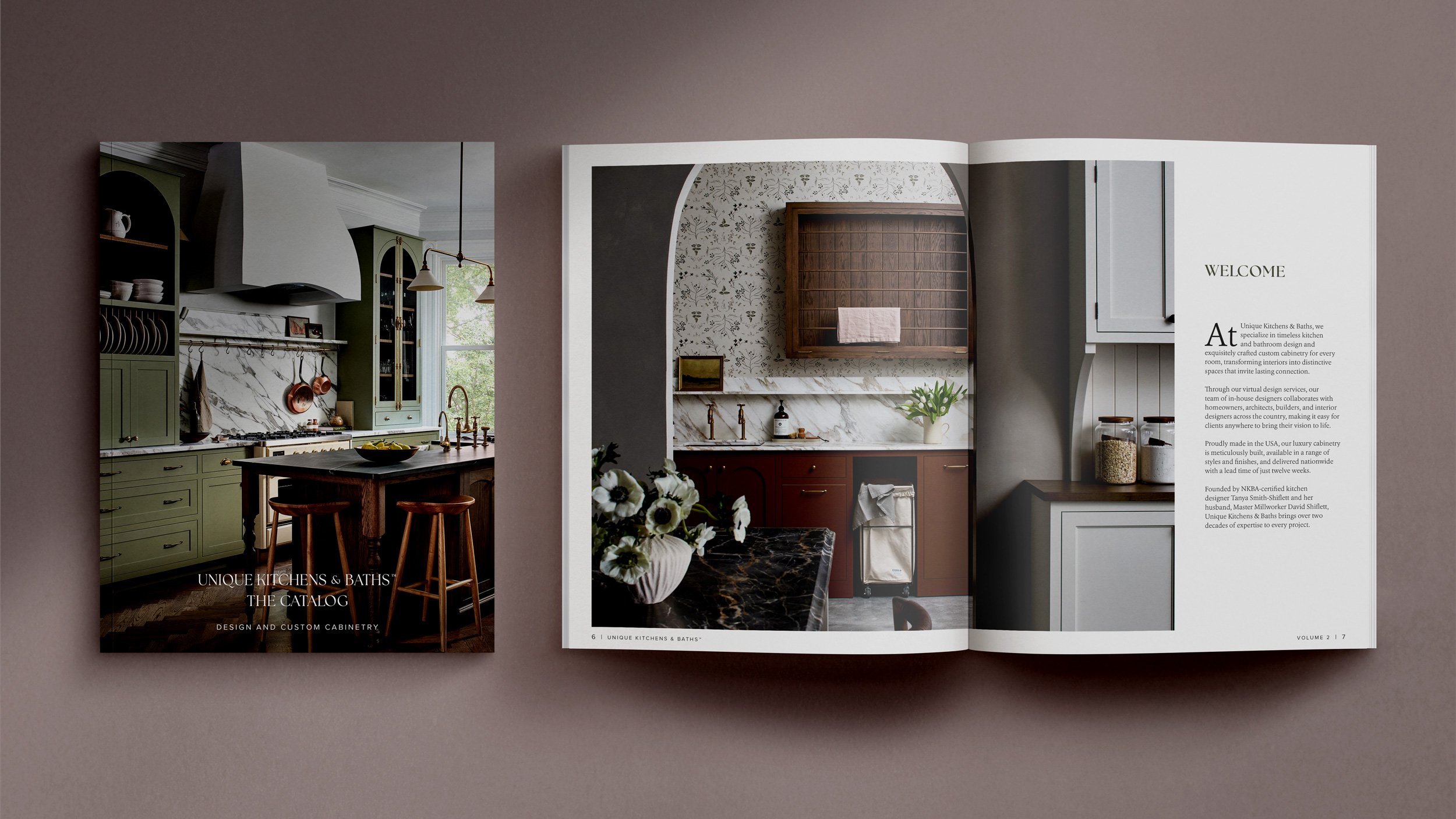 Open catalog showing kitchen design images with green cabinets on the left page and a brown and marble kitchen on the right page.