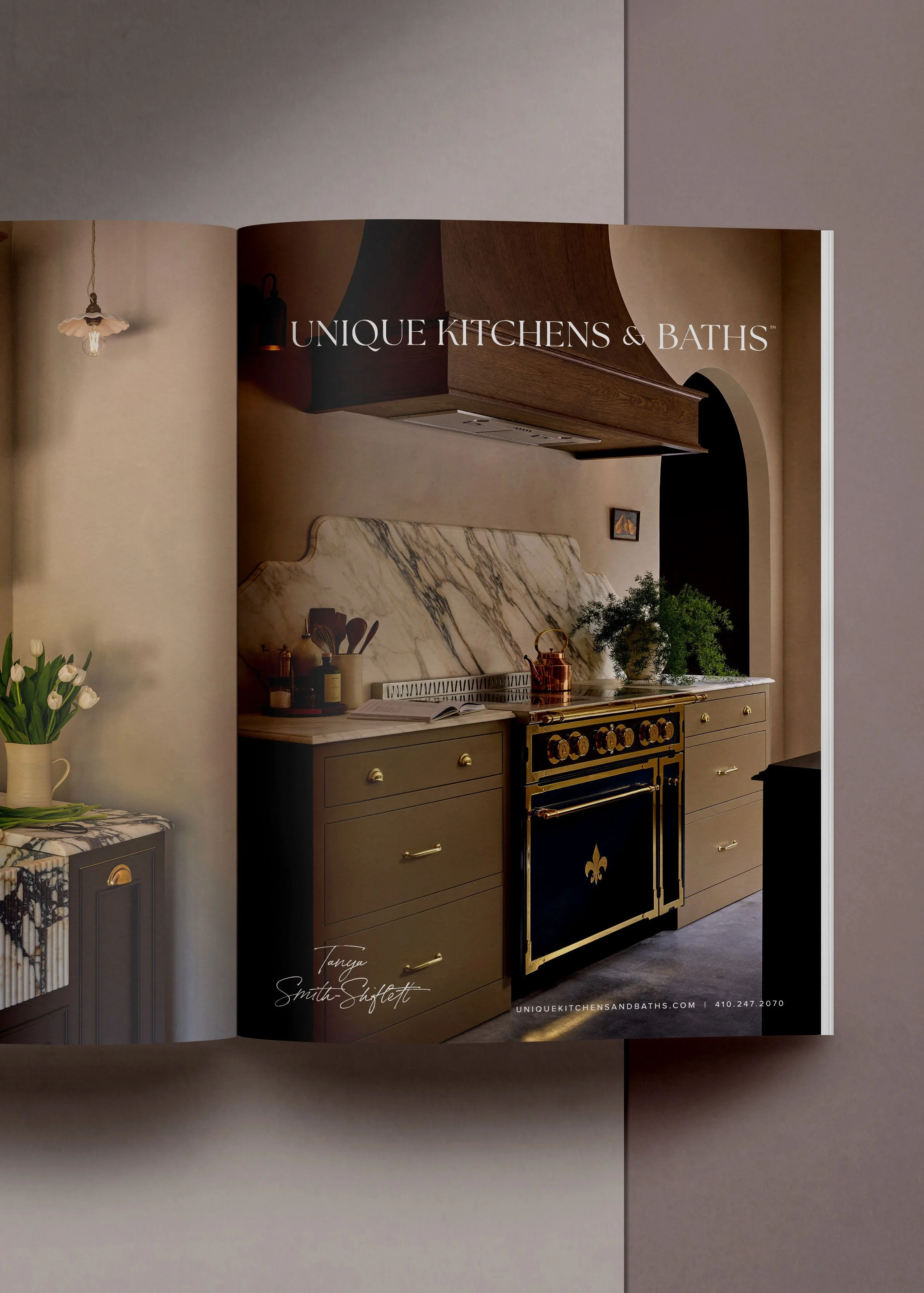 Magazine page showing a kitchen with black and gold stove, marble backsplash, wooden range hood, and green plants, titled "Unique Kitchens & Baths".