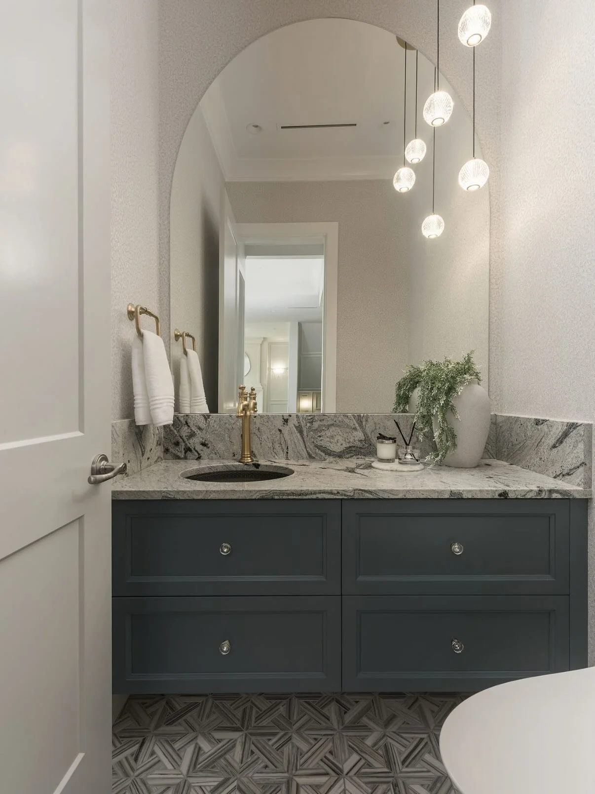 An exploration of texture, tone, and timeless form.
This powder room balances the warmth of sculptural brass with the organic movement of natural@stone and the artistry of a hand-etched bronze basin. Every detail considered, every surface deliberate 