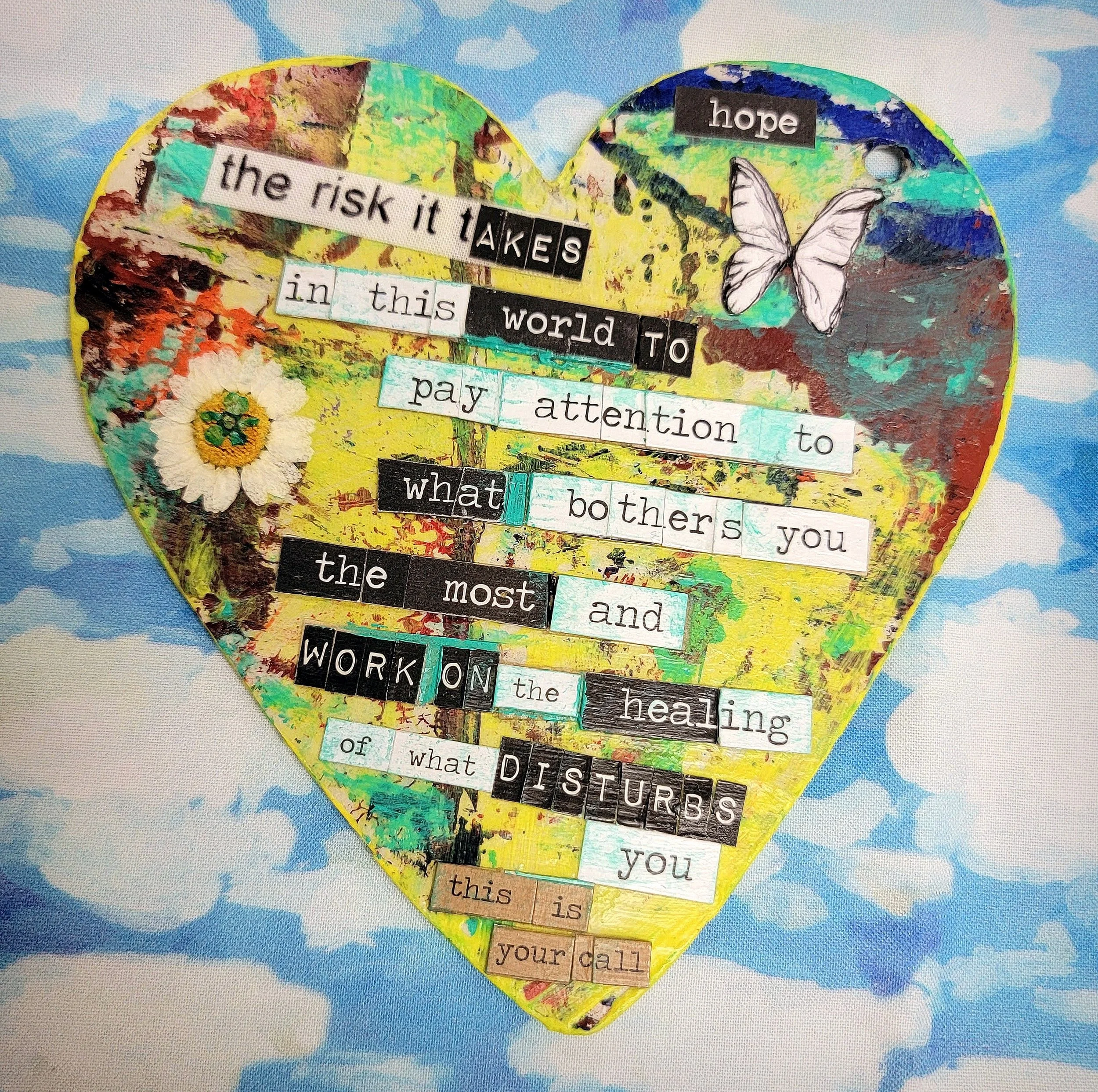 Mixed media yellow heart floating in a blue cloud studded sky, with expressive healing words in the heart.