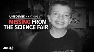 A young boy smiling in a black-and-white photo with a headline about an unsolved missing person case from a science fair.