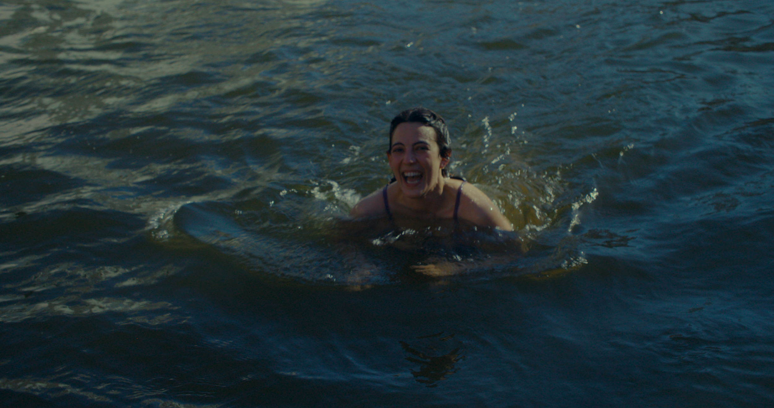 Woman smiling and swimming in a body of water.
