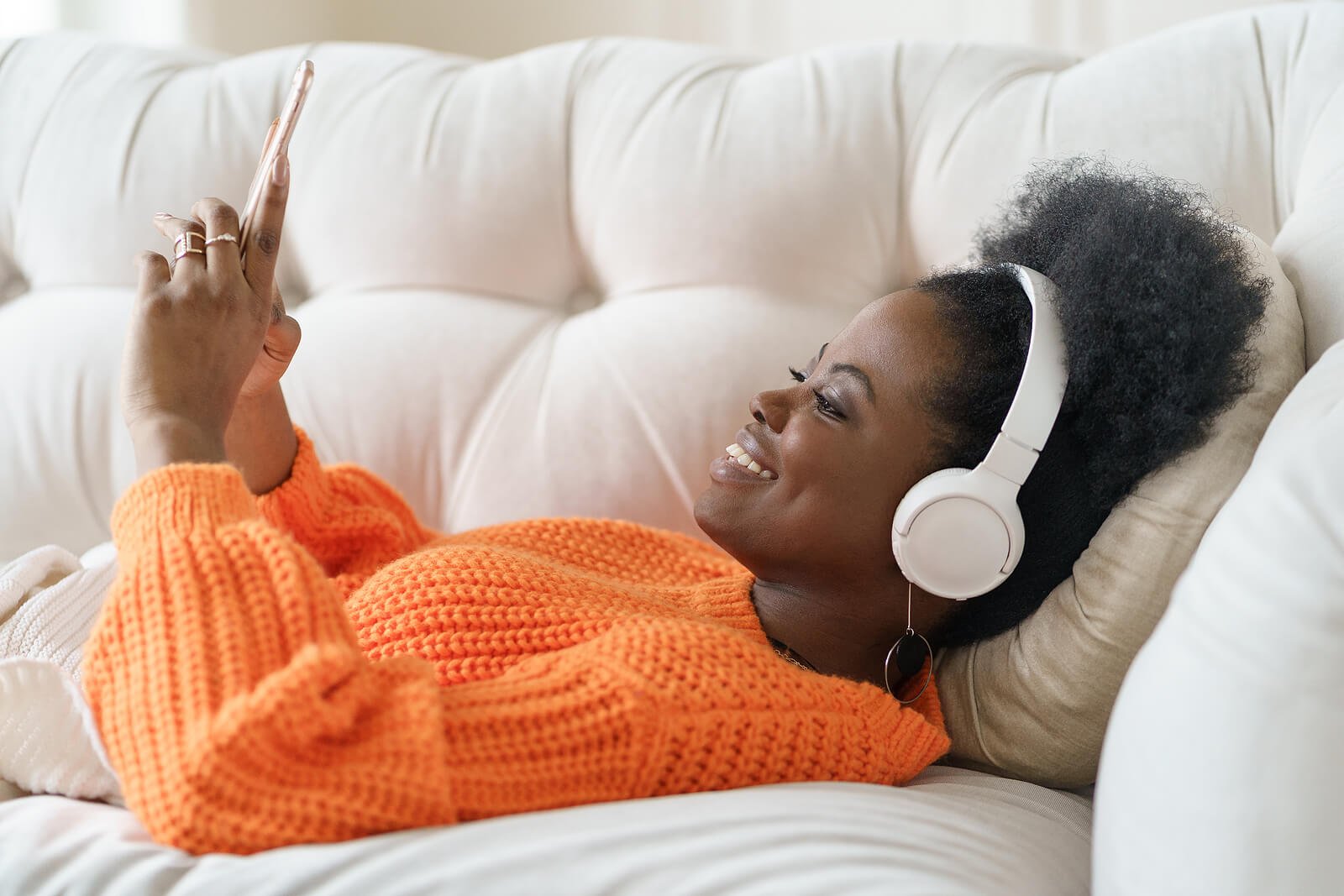 A woman laying down listening to music & smiling. Showing someone who has learned how to build confidence with counseling or therapy for women in Brooklyn, Westchester, and Manhattan, New York, NY.