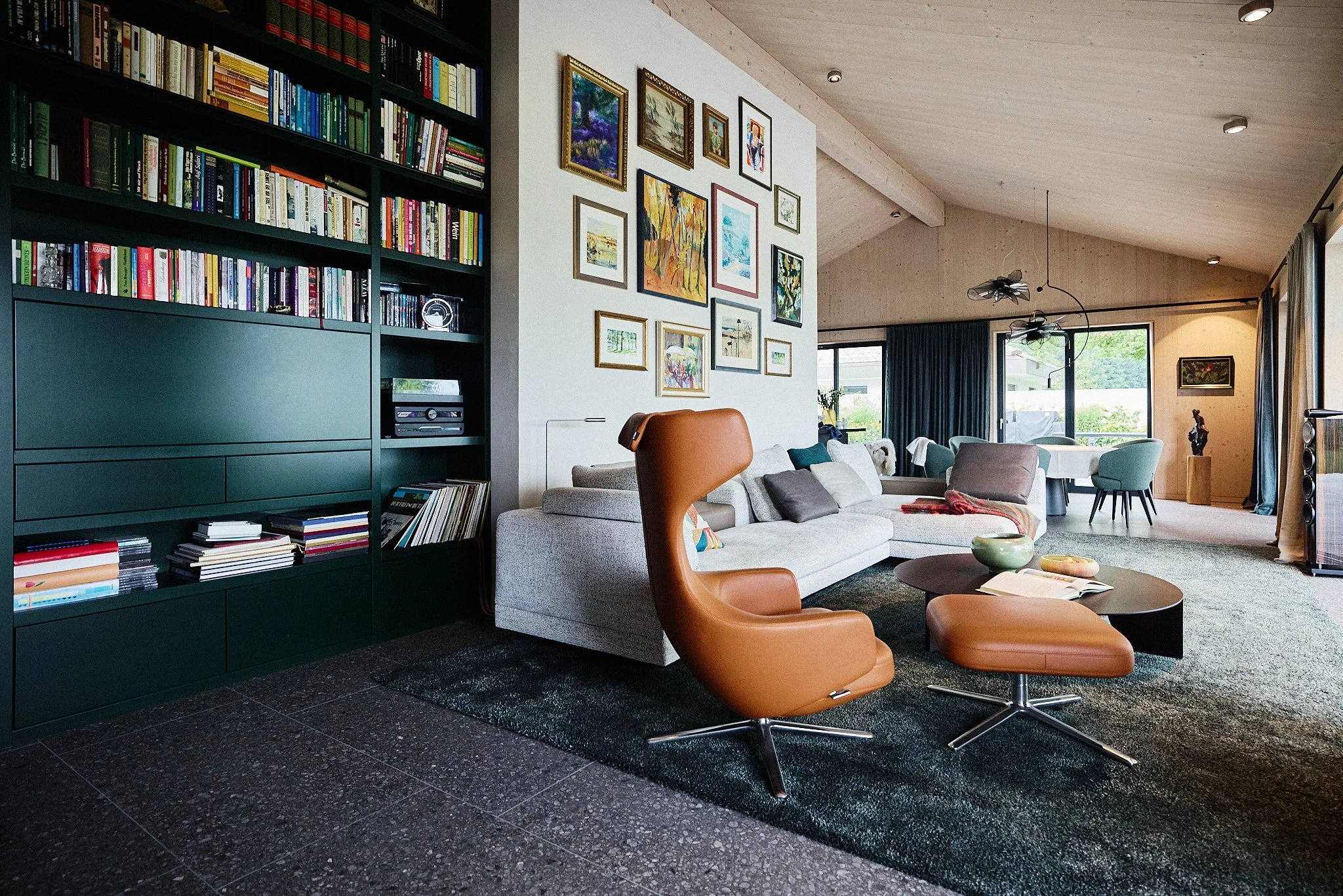 Offener Wohn- und Essbereich mit individuell entworfener Bibliothek mit integrierter Bar, ausgewählten Designmöbeln und kuratierter Kunstwand.