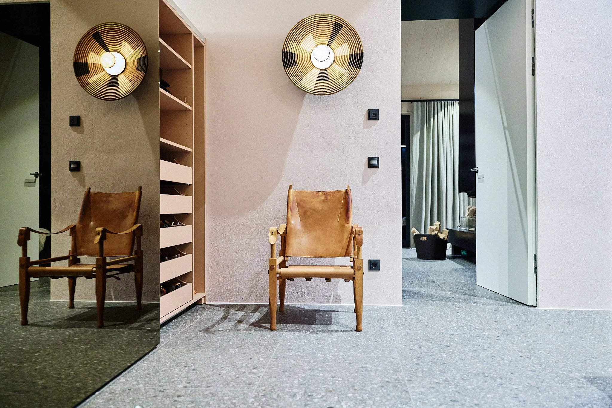 ingangsbereich eines Architektenhauses mit individuell entworfener Garderobe in Nude-Tönen, flächenbündigem bernsteinfarbenem Garderobenschrank und Vintage-Stuhl.