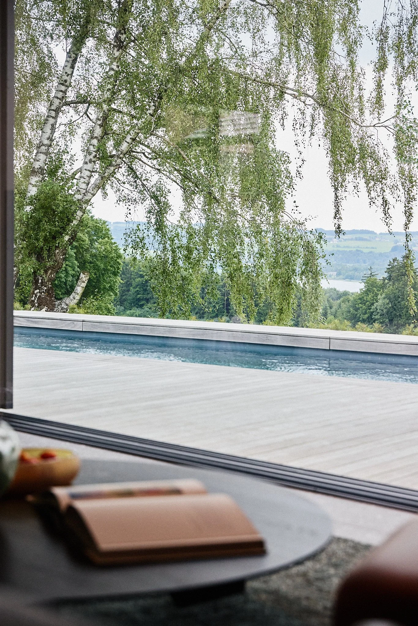 Blick aus dem Wohnbereich über Terrasse und Pool in die Landschaft des Salzburger Landes.