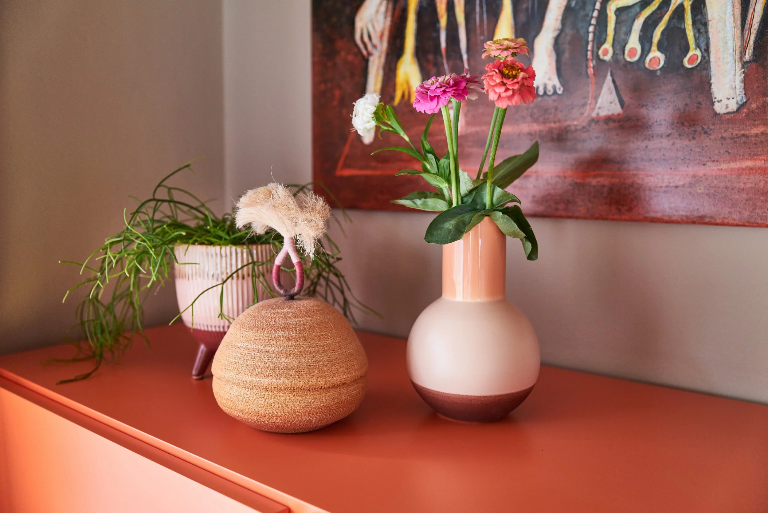 Peachfarbenes Möbel mit persönlichen Objekten und Kunst als Teil des Farb- und Materialkonzepts.