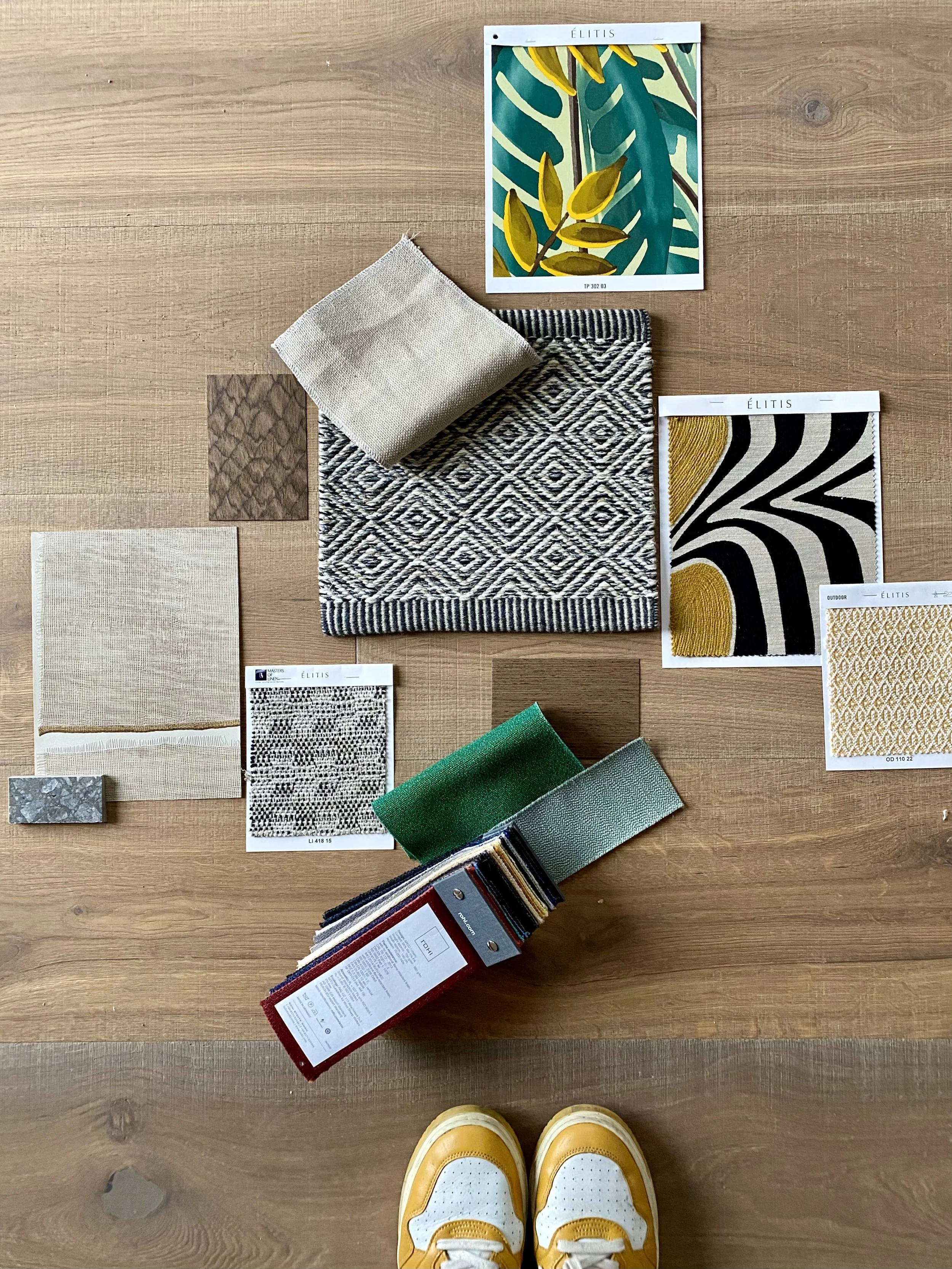 Material- und Farbkonzept mit Stoffen, Teppichmustern, Holz, Naturtönen, Grün und grafischen Textilien.