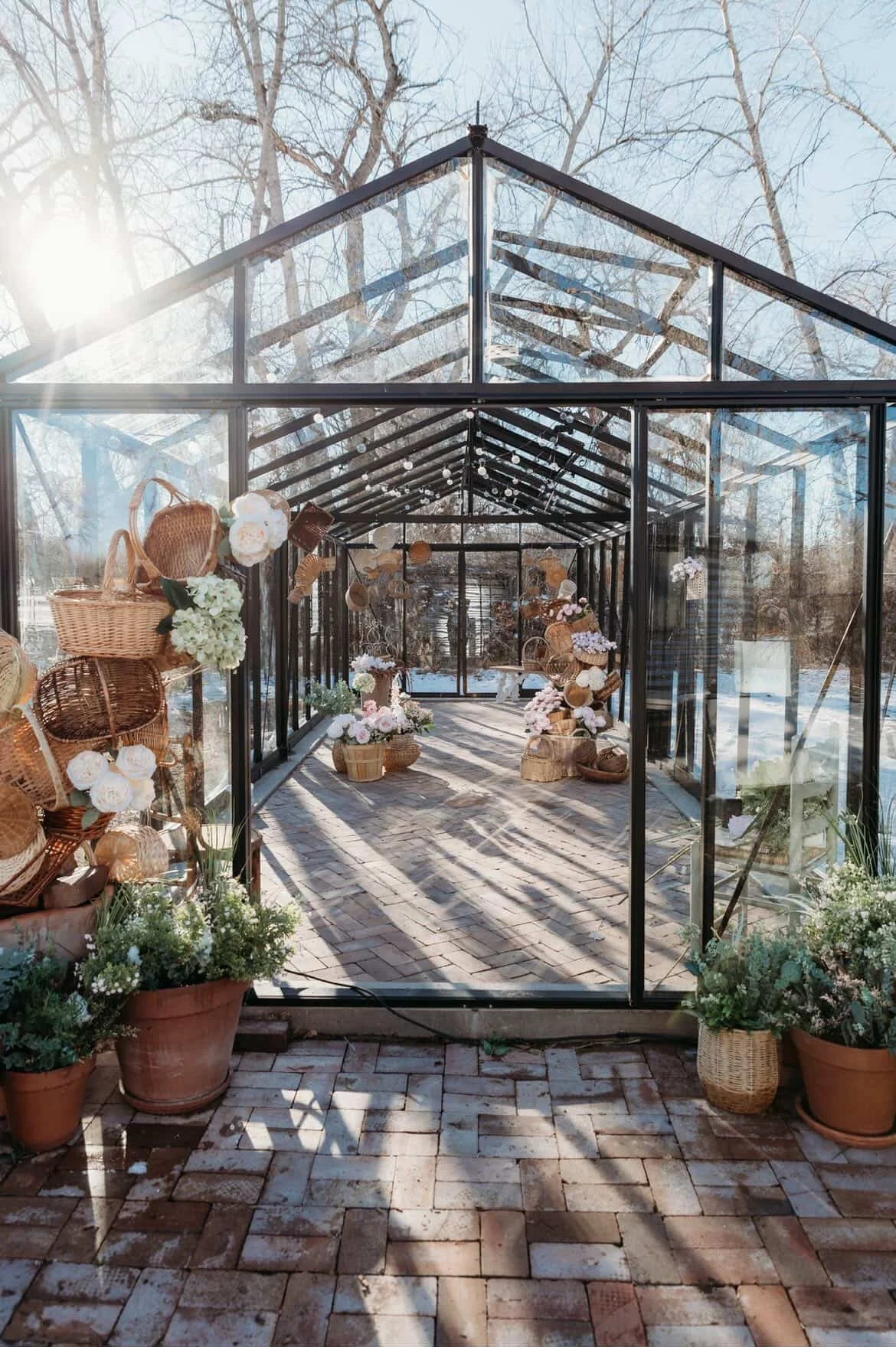 A vintage black truck with a spare tire on the back and a round sign on the door that reads 'Farm Fresh Pumpkins'. There is a small container with a red plaid pattern hanging from the side mirror. The truck is parked on a gravel surface with greenery and trees in the background.