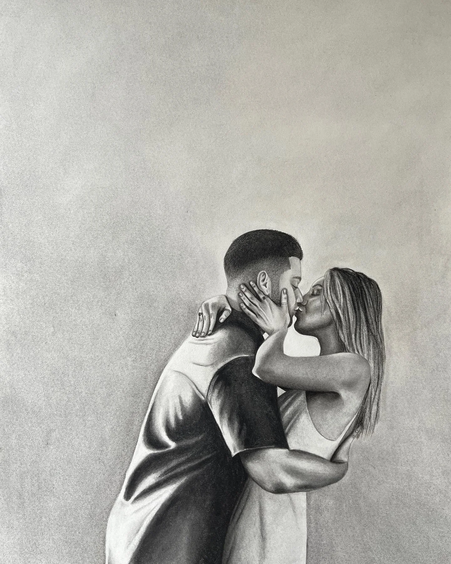 Realistic charcoal portrait of a couple embracing and kissing.
