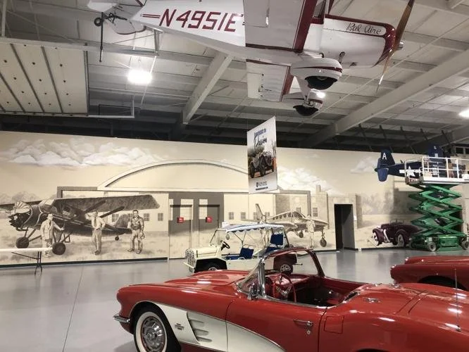 Large-scale historical mural inside the Hangar at Kruse Plaza in Auburn, Indiana, depicting local aviation and automotive history.