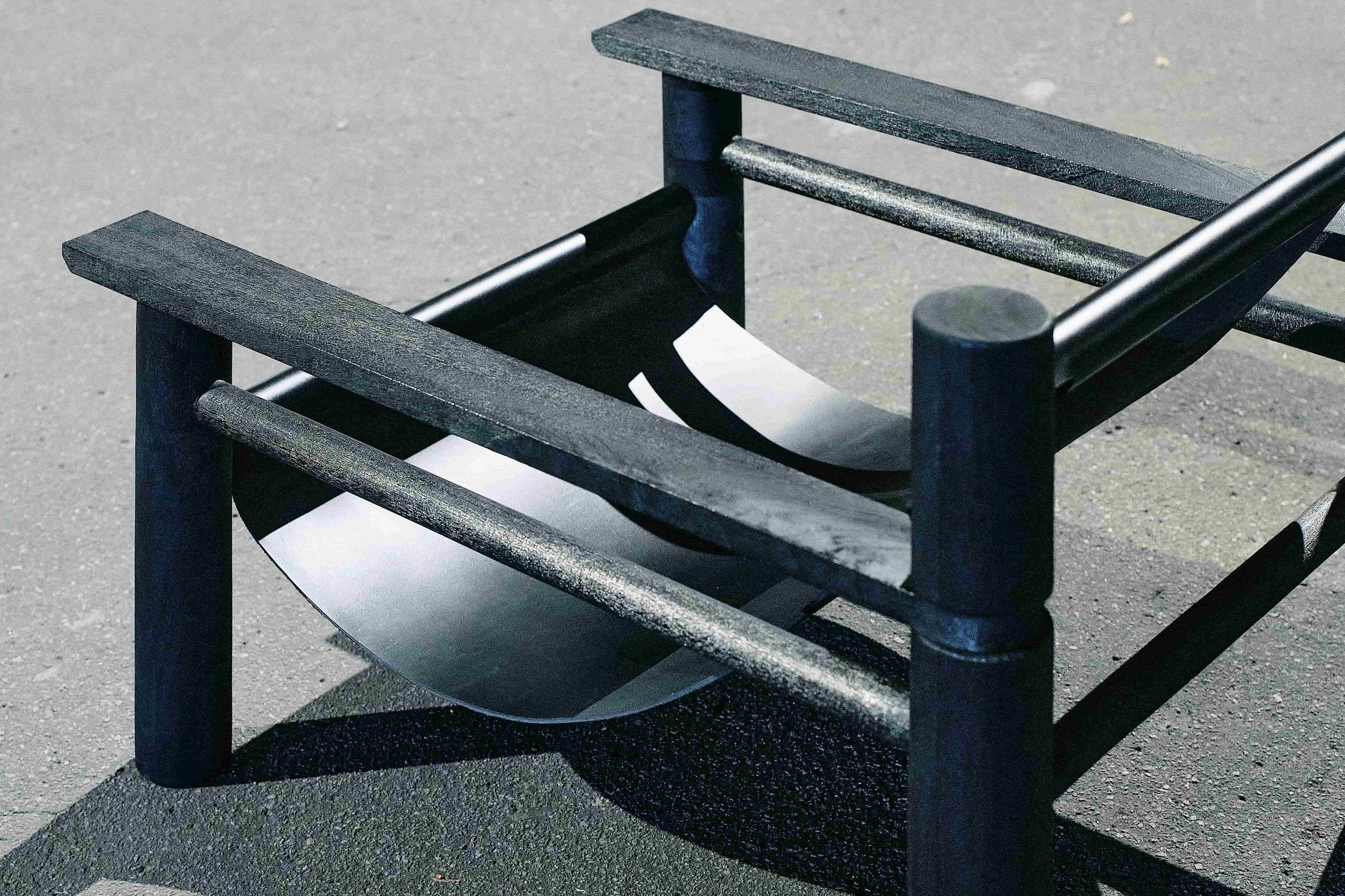 Modern black outdoor bench with a minimalist design on a concrete surface.