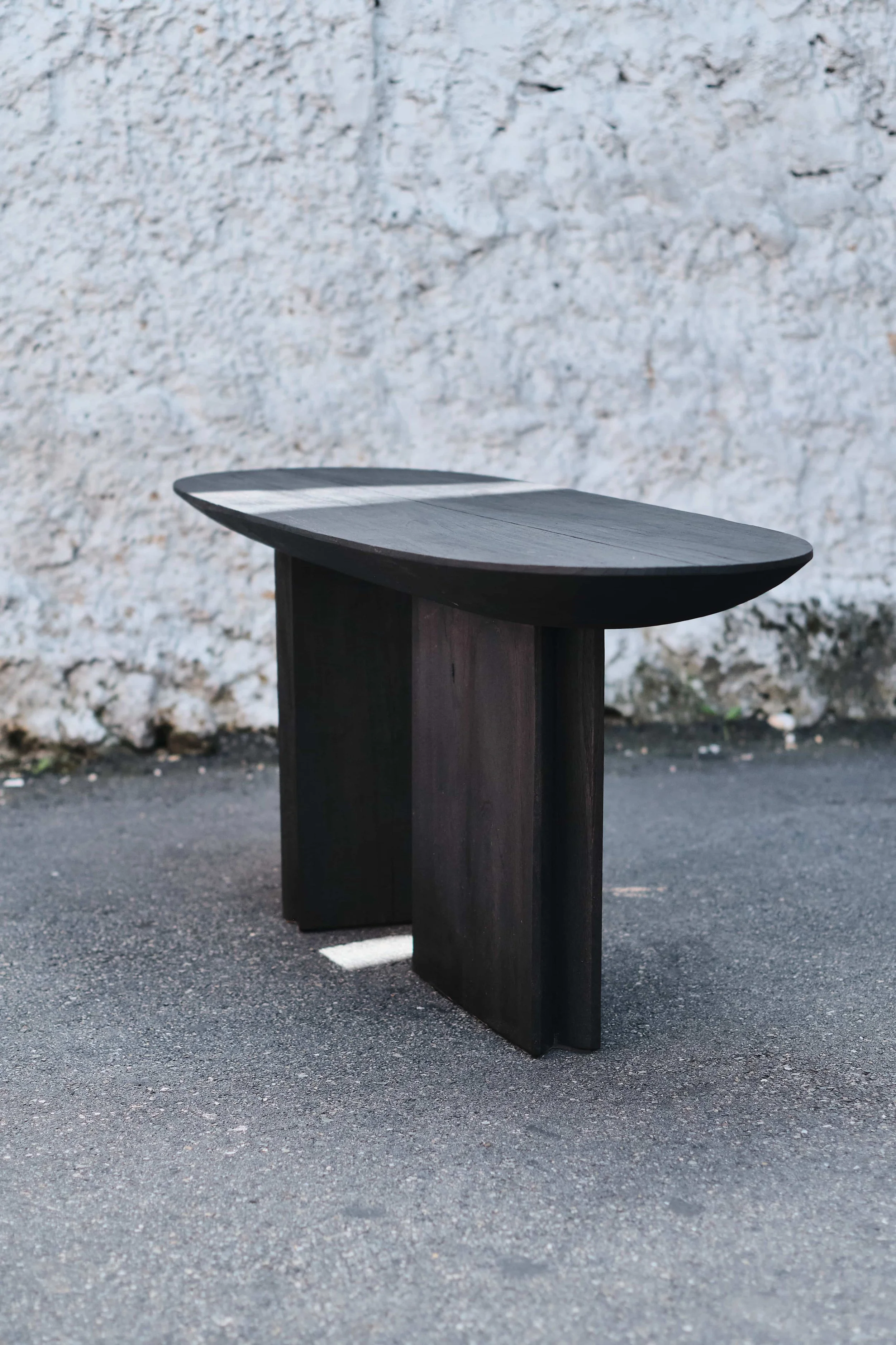 Modern dark wood bench in outdoor setting against textured wall
