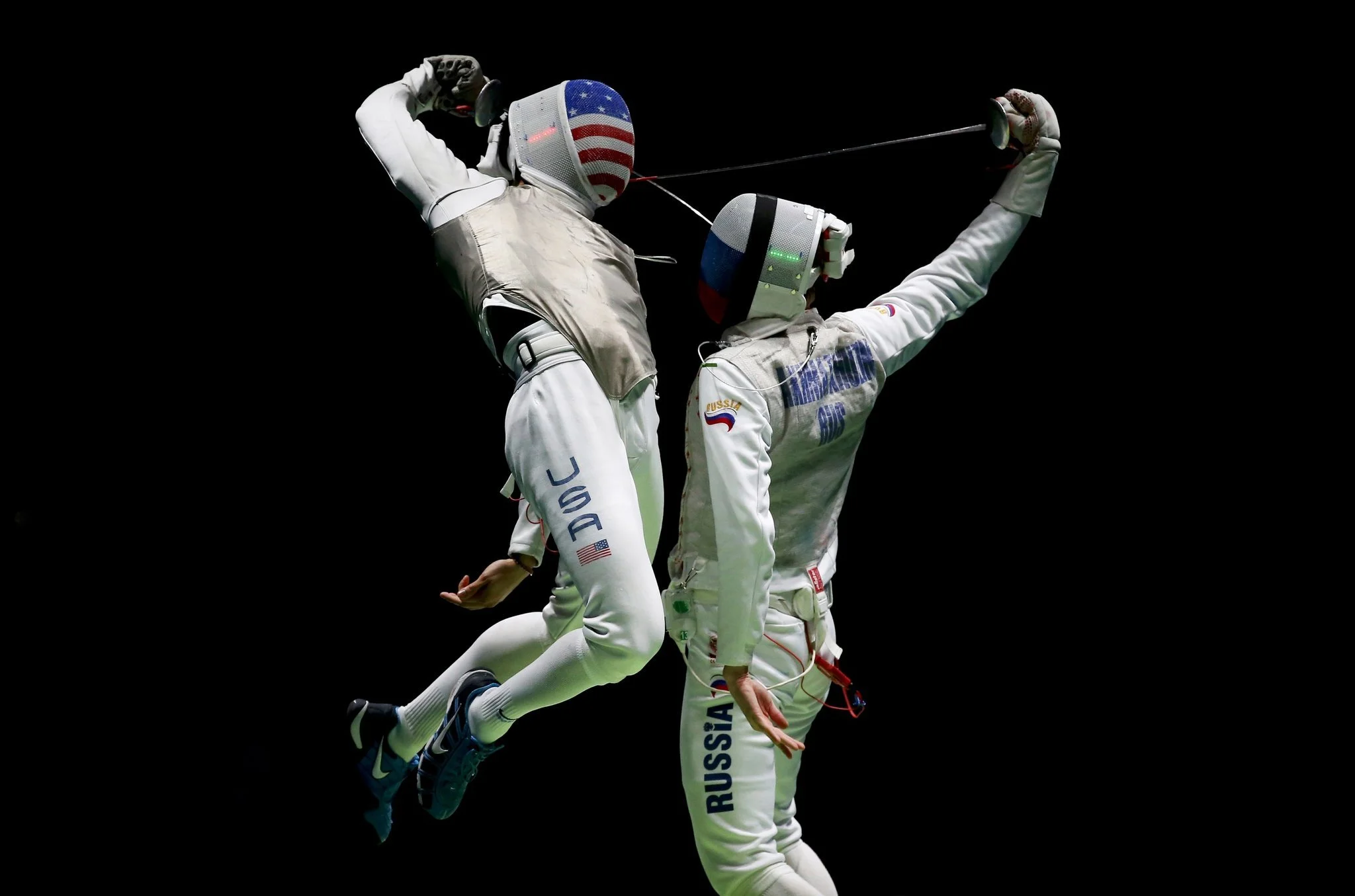 Two fencers from Russia competing in a fencing match, with one lunging at the other, against a black background.