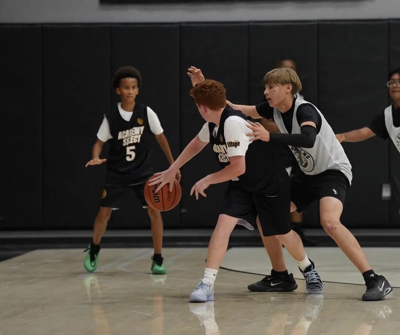 Two young basketball players competing on an indoor court, one player dribbling the ball while the other tries to defend. Background shows other players and a scoreboard displaying 8:07 minutes remaining and a score of 36-1. Text overlaid on the image reads 'GREAT TRAINING'.