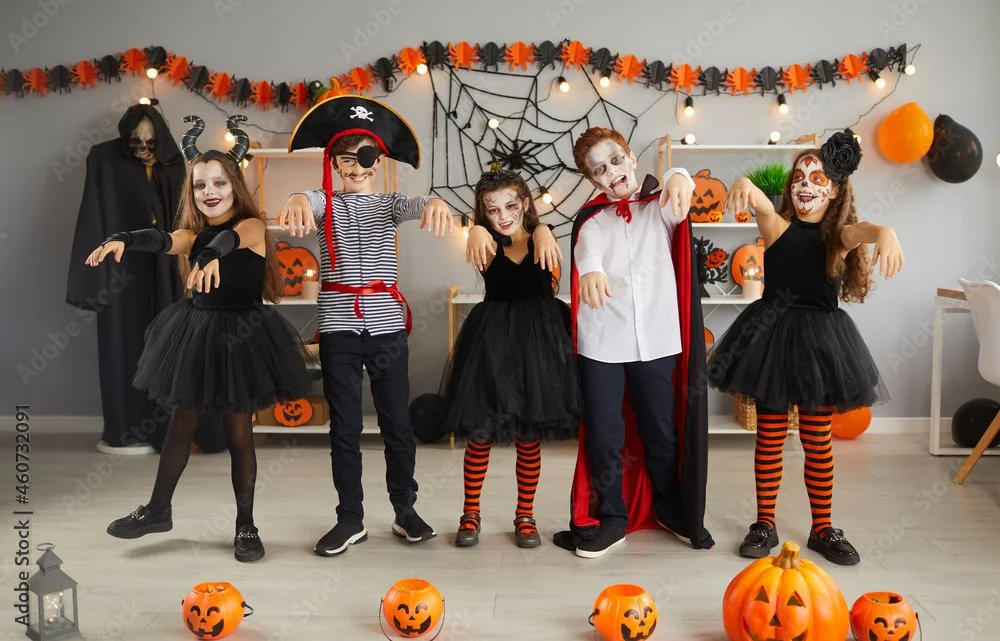 hildren dressed in Halloween costumes posing in a dance party setting with pumpkins and decorations.