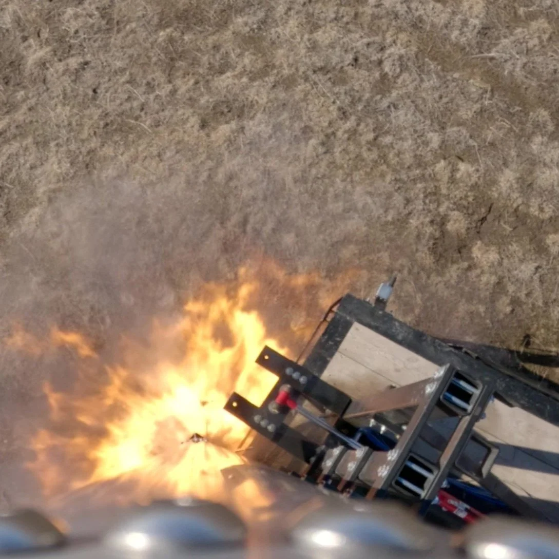 A rocket or missile igniting on launch pad with flames and smoke at night, on dry, dirt ground.