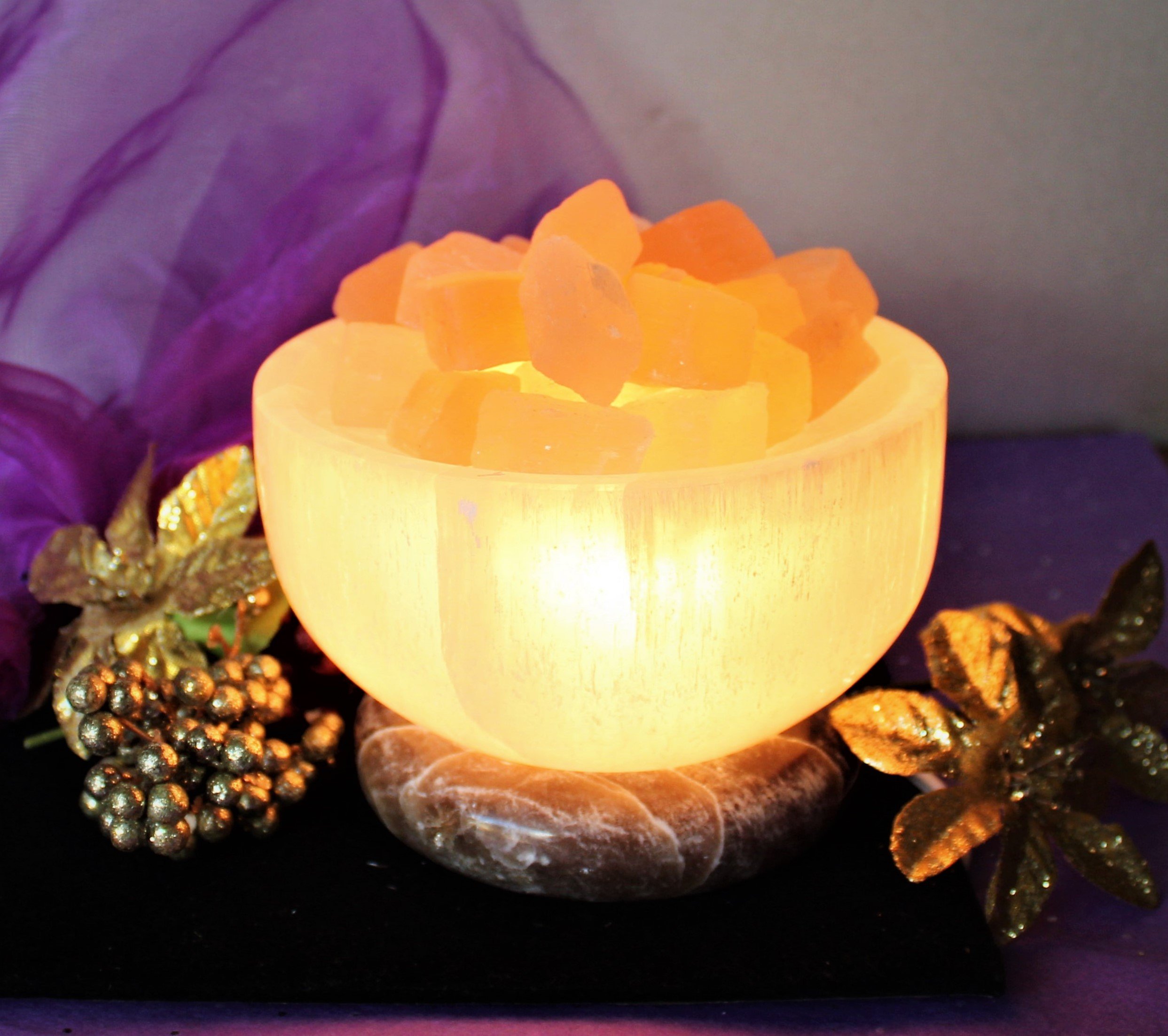 Transform your space with a glowing White Selenite Bowl filled with peach selenite cubes. Resting on an onyx base, it radiates a mesmerizing, serene, and spiritual light.