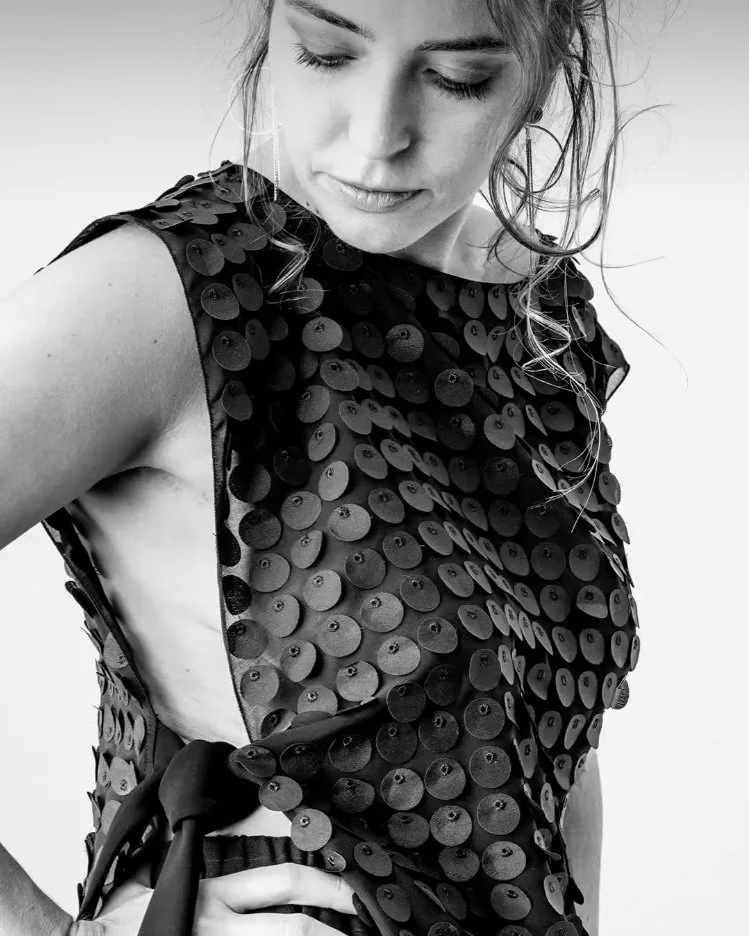 Femme portant une robe noire décorée de sequins, vue de côté en noir et blanc.