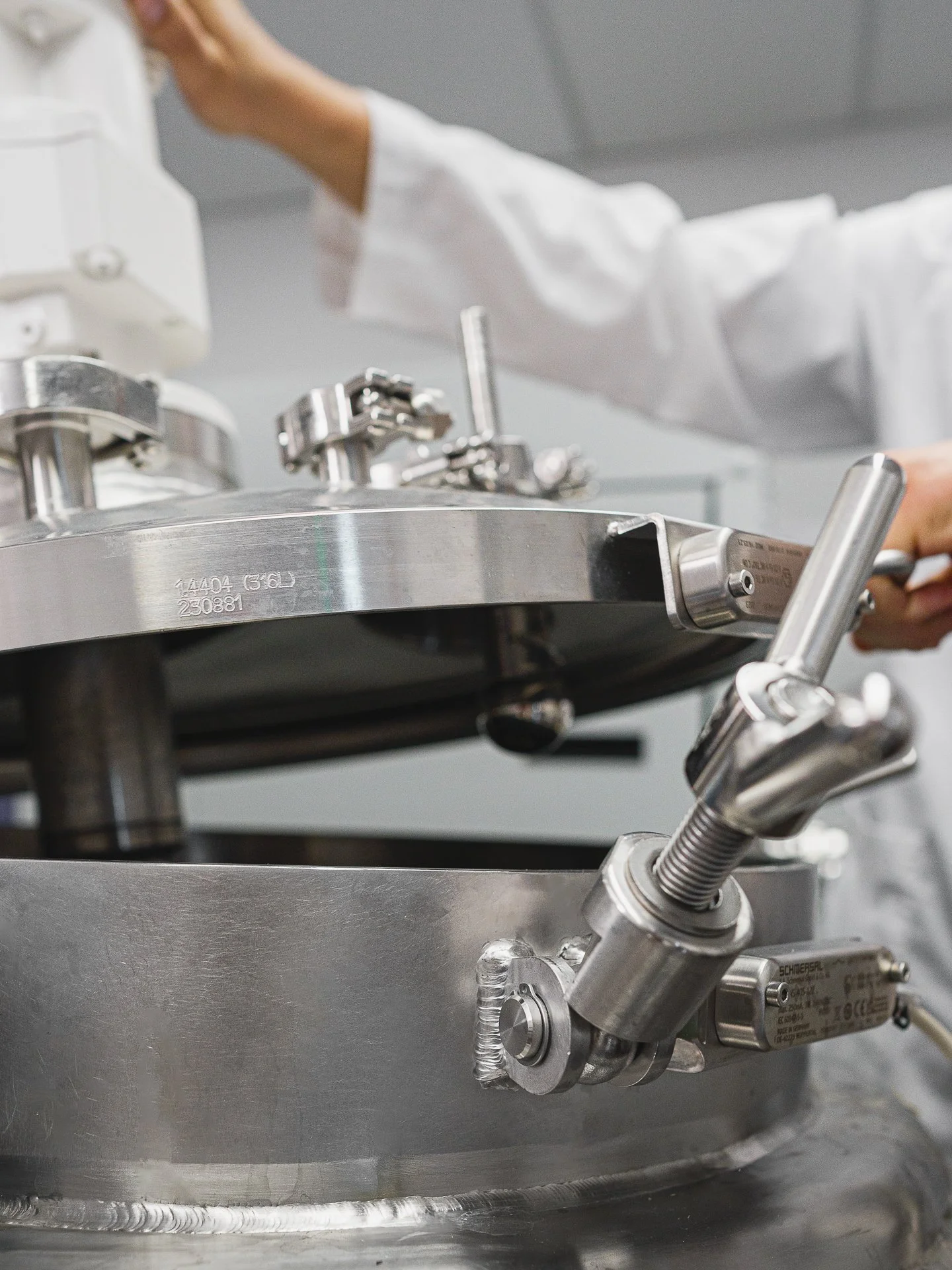 Une machine en acier inoxydable utilisée probablement en laboratoire ou pour la fabrication, avec des attaches et des composants mécaniques apparents.