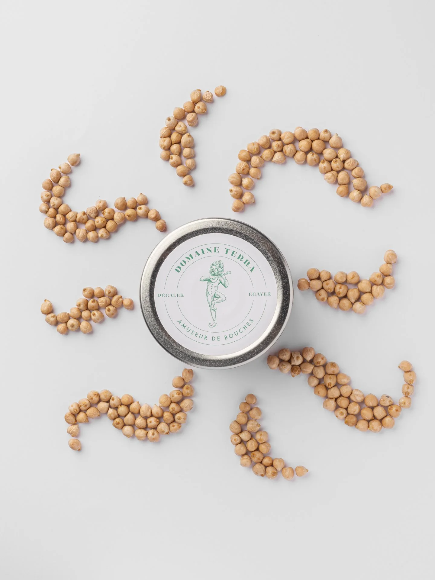 Une boîte métallique avec une étiquette verte et une illustration d'une figure humaine portant une tête de houblon est entourée de grains de pois chiches disposés en spirale sur un fond blanc.