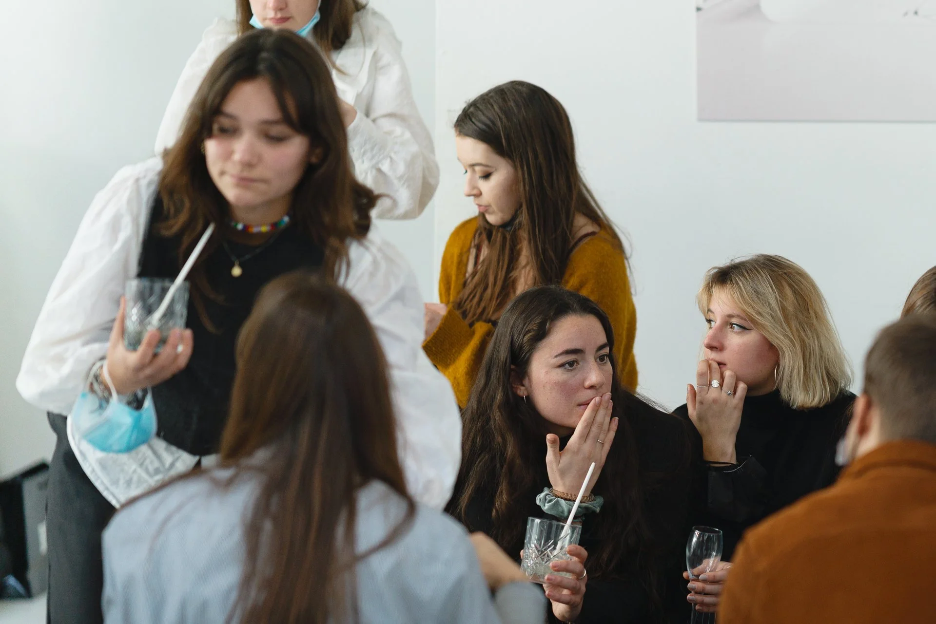 Groupe de jeunes femmes assises autour d'une table, discutant et buvant des boissons, dans un environnement intérieur