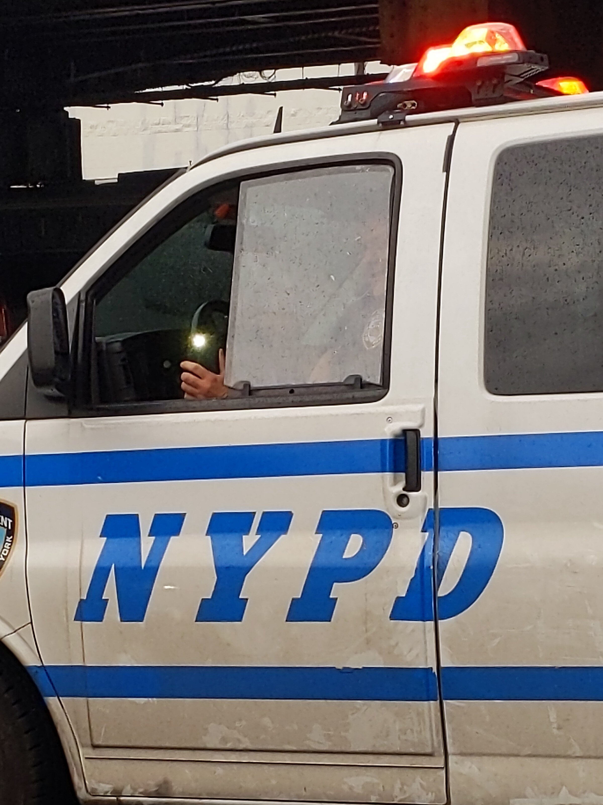  An NYPD officer uses a cell phone to record video of people entering and leaving an action. 