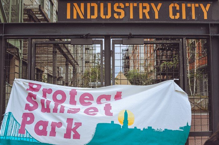  Protestors hang a banner at Industry City in Sunset Park, Brooklyn 