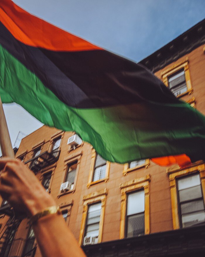  A protestor flies the red, black, and green flag of Black liberation. 
