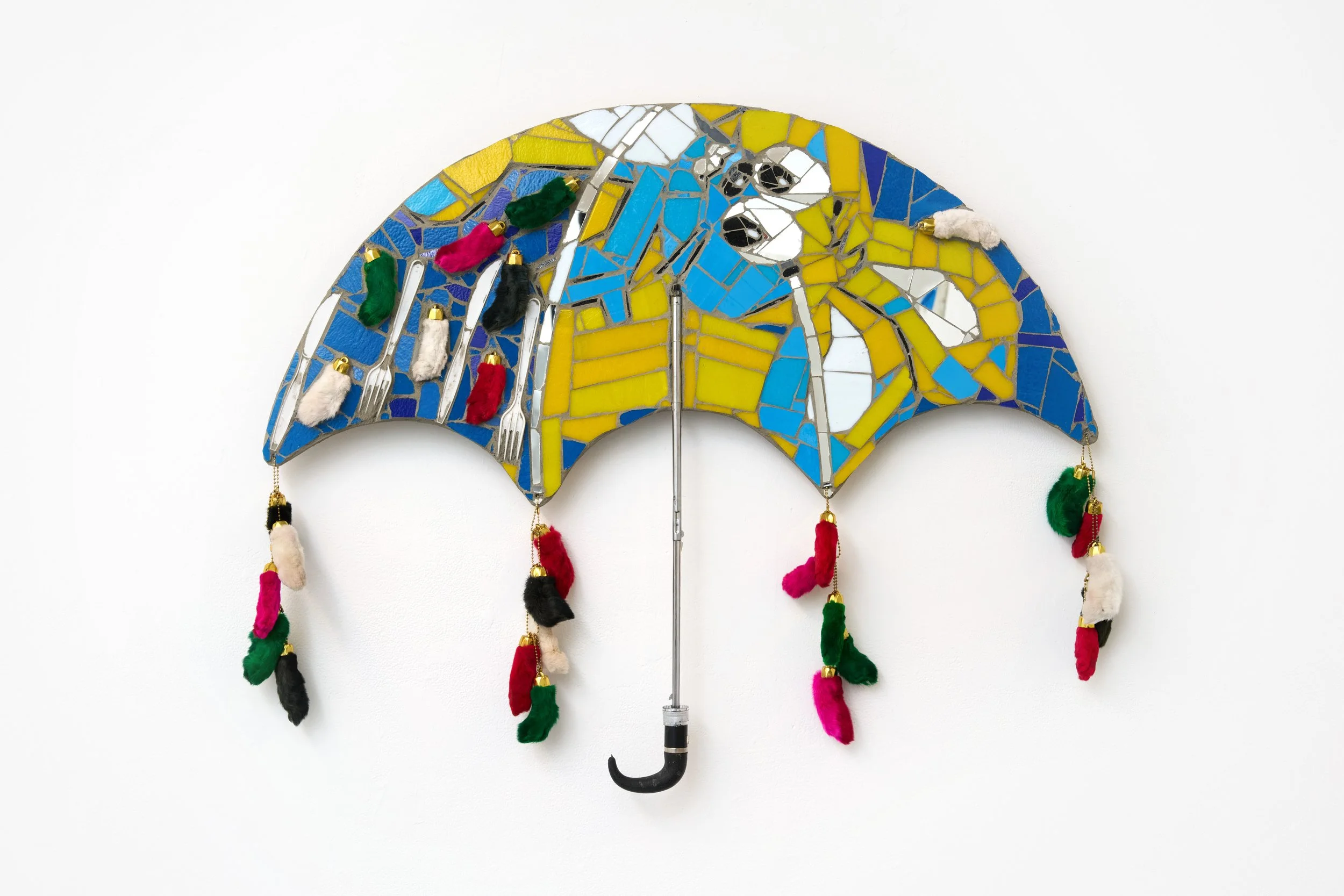 Marco DaSilva, "Favorite Toy, Curbside Shield, 
" 2025, Plastic cutlery, rabbit's foot keychains, umbrella arm, mosaic glass, mirror and mortar on compressed foam board, 38 × 29 in.